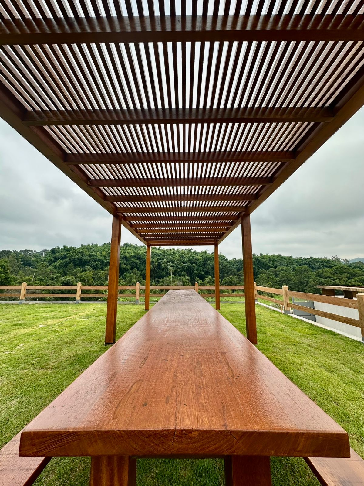 Mesa de madeira sob pergolado no jardim