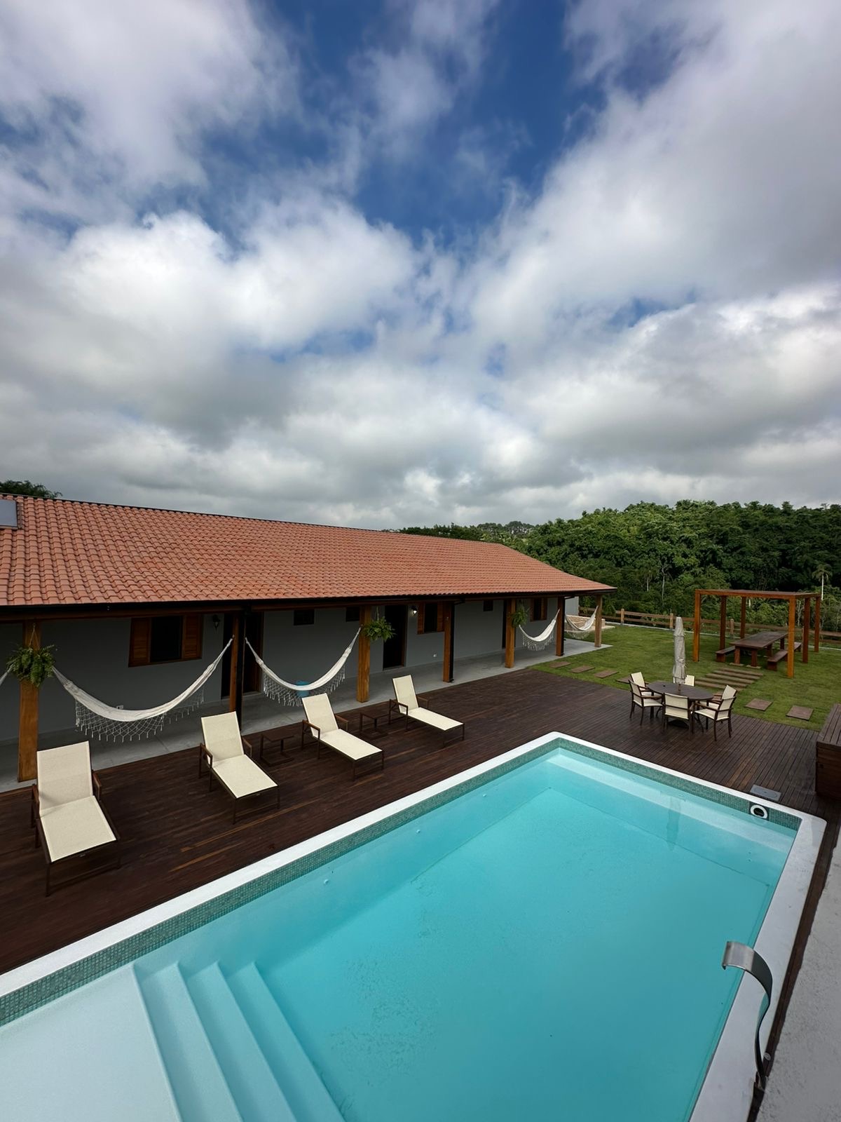 Vista da piscina com redes e jardim ao fundo