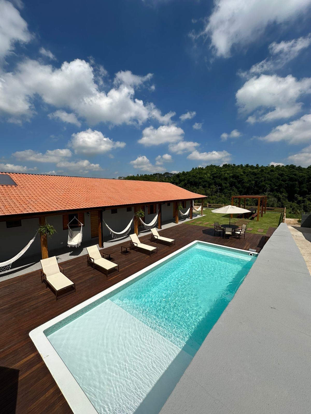 Vista panorâmica da piscina, varanda e áreas verdes